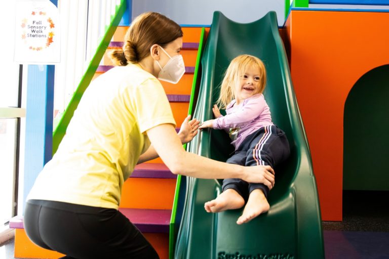 photo of a child on a slide with an aba therapist. used for the Oswego ABA clinic page.