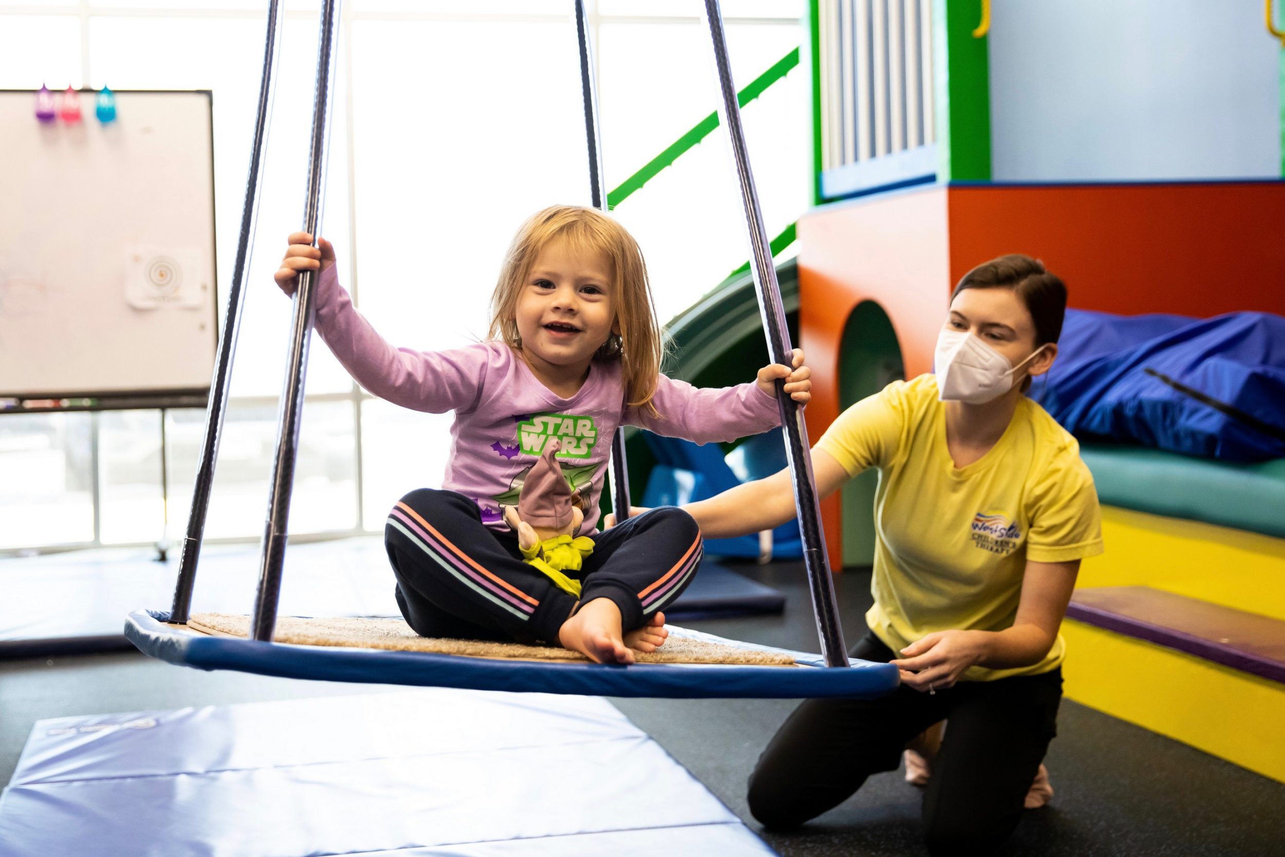 photo of a child on a swing with a pediatric aba therapist at Westside in Illinois