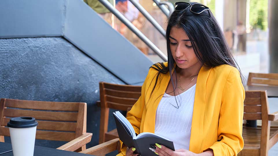 Mother reading book by coffee shop