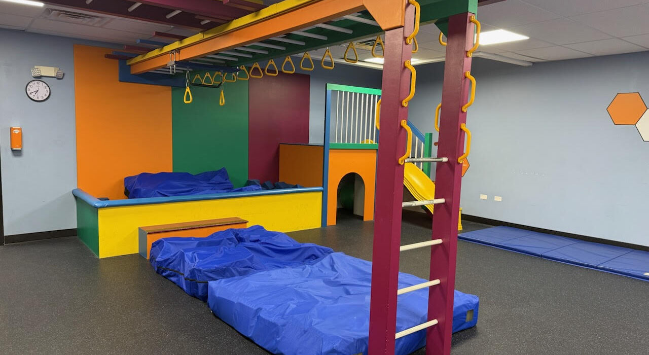 indoor pediatric sensory or occupational therapy gym equipped with colorful climbing structures