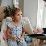 A young girl sitting attentively during a speech-language evaluation with a pediatric therapist taking notes.