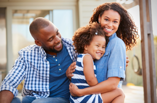A happy family with a young child enjoying time outdoors together at a sensory-friendly community event near Chicago.