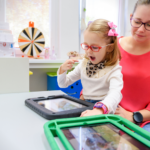A speech therapist working with a young girl using a tablet during a pediatric speech therapy session.