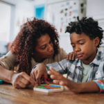 A mother supporting her child with autism during a puzzle activity at home, representing autism caregiver mental health awareness.
