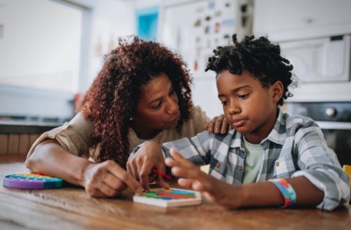 A mother supporting her child with autism during a puzzle activity at home, representing autism caregiver mental health awareness.
