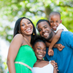 A smiling family of four embracing outdoors, representing sensory-friendly summer events for families in the Chicago area.