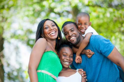 A smiling family of four embracing outdoors, representing sensory-friendly summer events for families in the Chicago area.