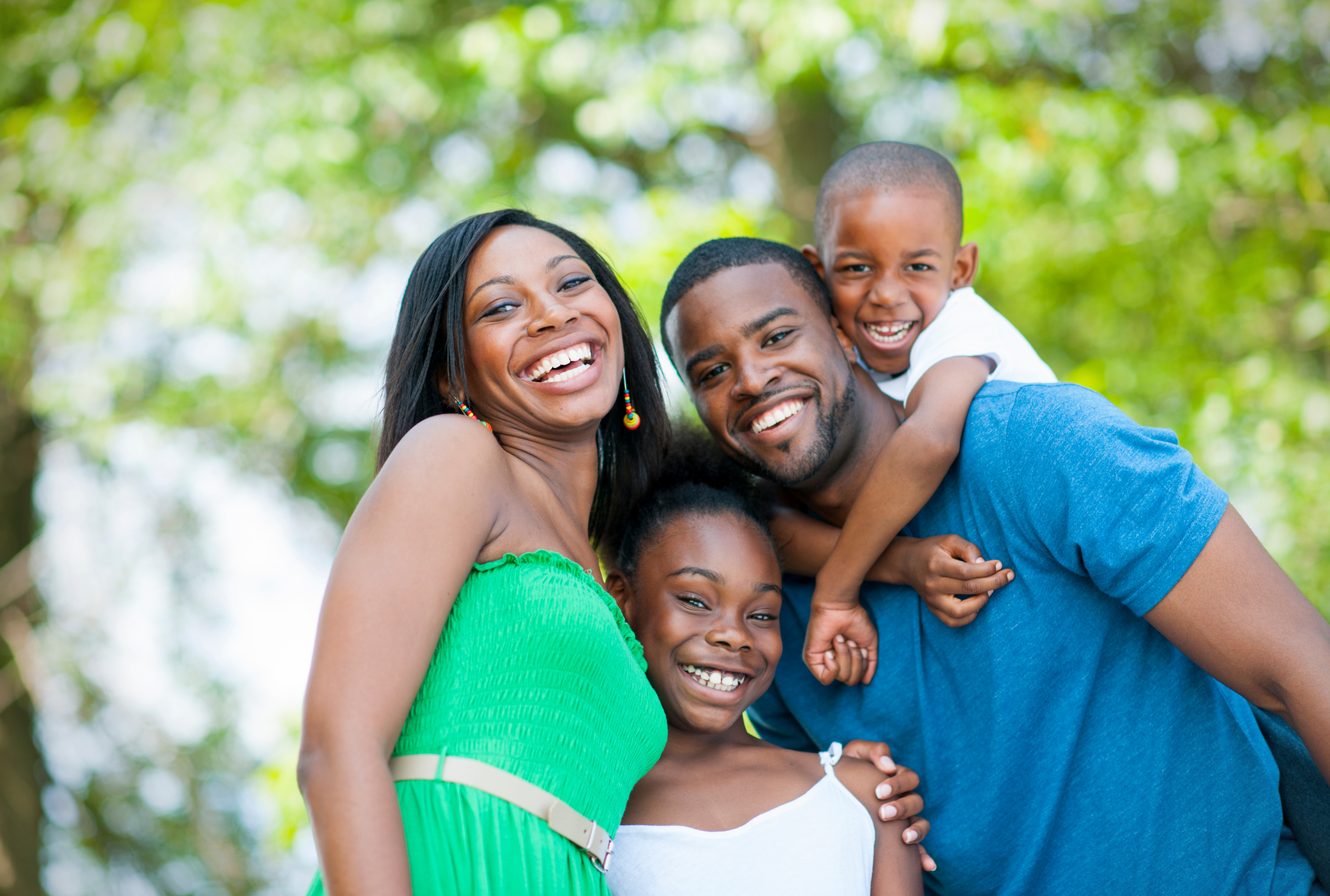 A smiling family of four embracing outdoors, representing sensory-friendly summer events for families in the Chicago area.