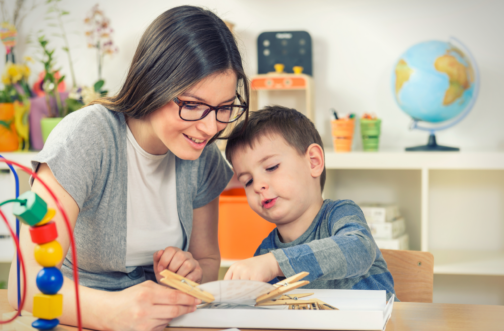 A therapist working one-on-one with a young child during an ABA therapy session in a pediatric clinic.