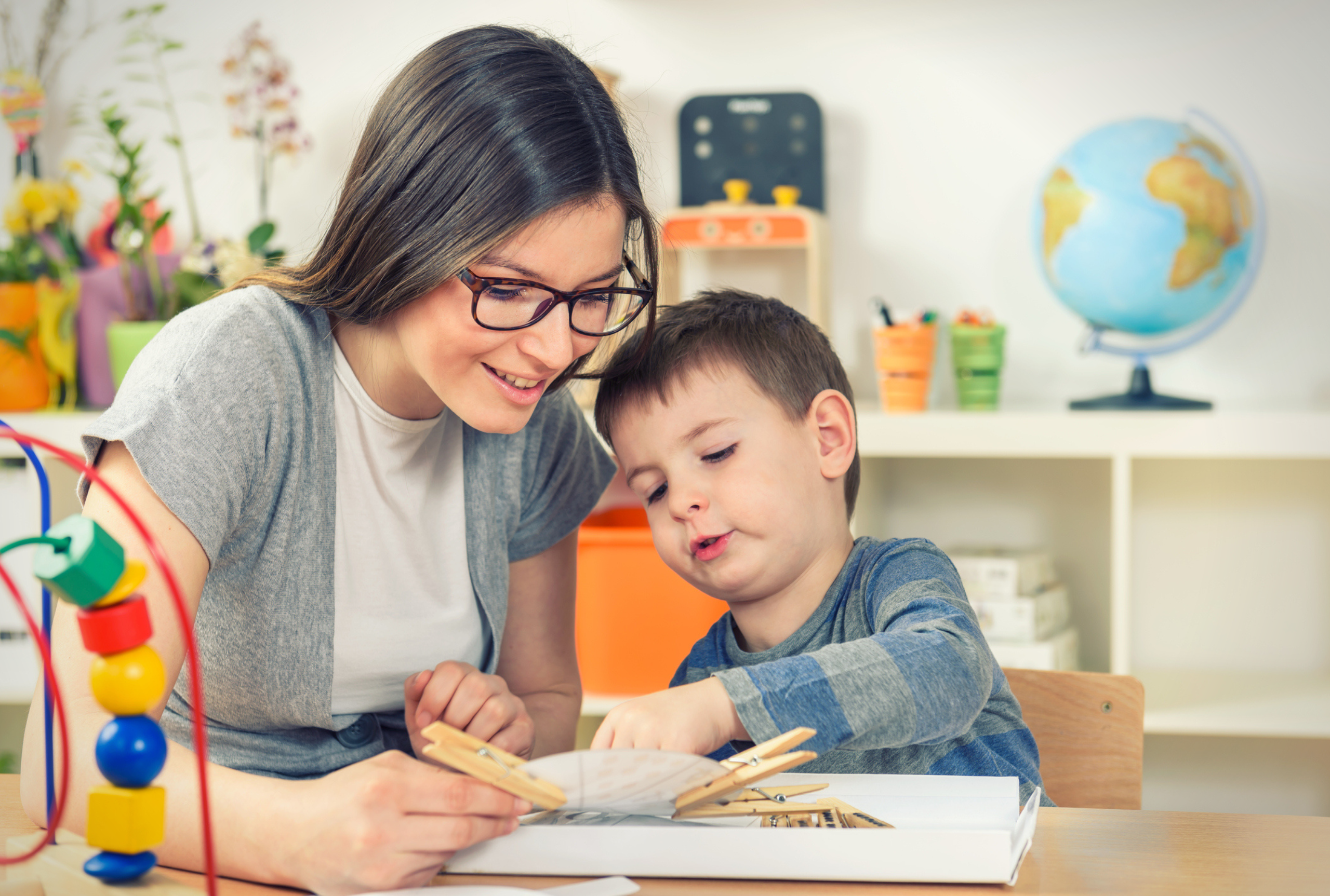 A therapist working one-on-one with a young child during an ABA therapy session in a pediatric clinic.