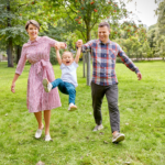 A family with a young child playing outdoors at a park, representing sensory-friendly summer events for families in the Chicago area.