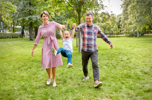 A family with a young child playing outdoors at a park, representing sensory-friendly summer events for families in the Chicago area.