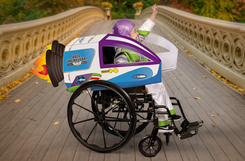 A child in a space ranger costume cheers with a raised fist while seated in a wheelchair transformed into a spaceship with a costume cover, representing adaptive Halloween costume ideas for kids who use wheelchairs.